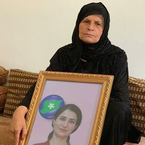 Hevrin Khalaf's mother, Souad Mohammad, is seen with an image of her daughter in this undated photo.