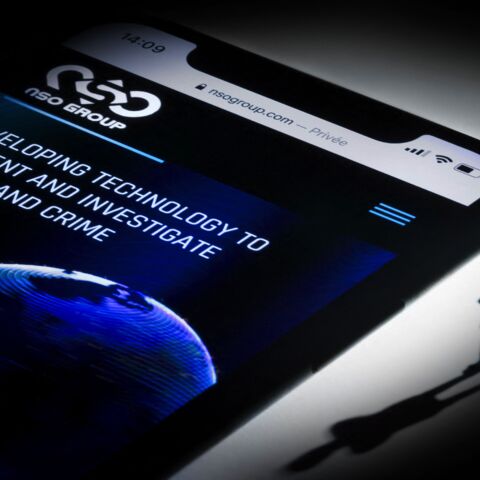 This studio photographic illustration shows a smartphone with the website of Israel's NSO Group.