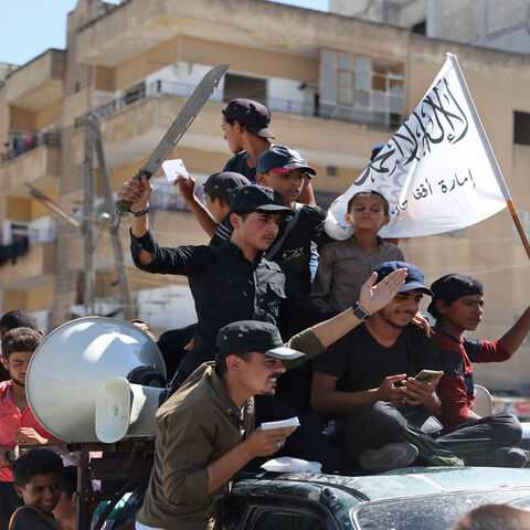 Members of Syria's top jihadist group Hayat Tahrir al-Sham, led by al-Qaeda's former Syria affiliate, parade with their flags and those of the Taliban's declared "Islamic Emirate of Afghanistan" through the rebel-held northwestern city of Idlib, Syria, Aug. 20, 2021.