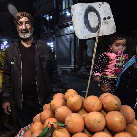 Egyptians smile for a photo as they buy fruits from a street vendor at a market in the Menufiya province north of Cairo on Feb. 22, 2018.  