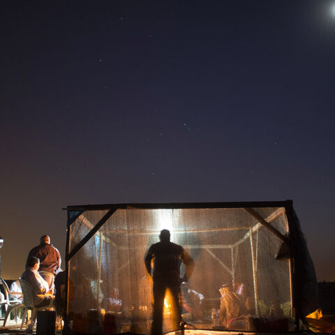 Bedouin men eat their dinner in a tent on Oct. 9, 2013, in the Bedouin village of Al-Arakib, Israel.