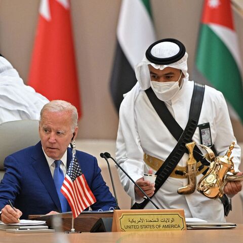 US President Joe Biden takes notes while an usher serves coffee during the Jeddah Security and Development Summit (GCC+3) at a hotel in Saudi Arabia's Red Sea coastal city of Jeddah on July 16, 2022. 