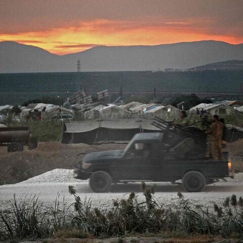 Members of the Hayat Tahrir al-Sham (HTS) jihadi group advance toward the village of Jindayris.