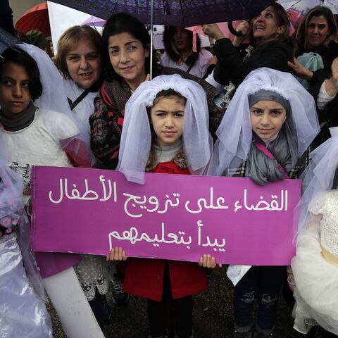 Young Lebanese girls disguised as brides hold a placard as they participate in a march against marriage before the age of 18, in the capital Beirut on March 2, 2019. The placard in Arabic reads "The end of child marriage begins by educating them".  (ANWAR AMRO/AFP via Getty Images)