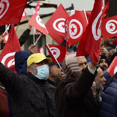 Tunisian protesters raise placards and national flags.