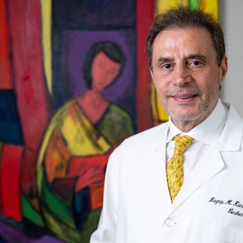 Hagop Kantarjian, M.D., poses with one of his favorite paintings, "Seated Woman with Red Guitar" (2021).