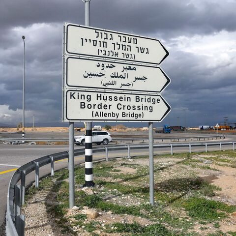 A car drives past a road signal indicating the Allenby (King Hussein) bridge crossing point to Jordan.