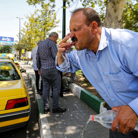 A man rinses his face with water from a bottle to cool off during a heat wave in Tehran on July 11, 2023. 