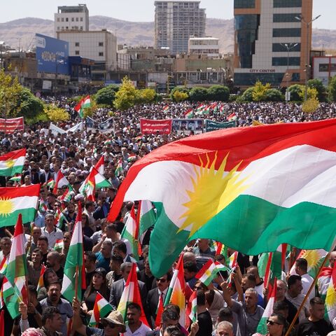 People in Dohuk city lift the regional flag during a rally over unpaid salaries in the autonomous Kurdish region of northern Iraq