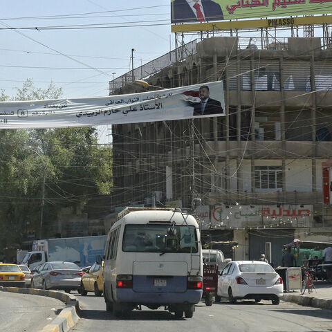 Iraqis drive past electoral billboards and placards of candidates for the upcoming parliamentary elections in Karrada district, Baghdad, Iraq, Sept. 19, 2021.