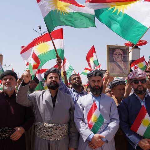 People lift the regional flag during a rally in Dohuk city.