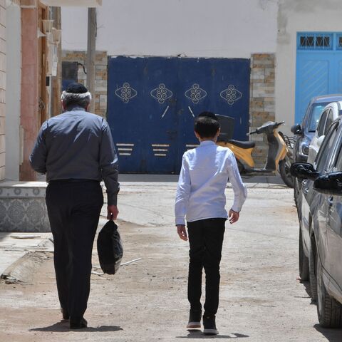 A Jewish man and a child walk through the Hara Kebira, the main Jewish quarter in the resort island of Djerba, near the Ghriba synagogue following a shooting spree by a police officer on the southern Tunisian island on May 10, 2023. Tunisian authorities were investigating the shootings that claimed five lives and sparked mass panic during a Jewish pilgrimage at Africa's oldest synagogue today. (Photo by FETHI BELAID / AFP) (Photo by FETHI BELAID/AFP via Getty Images)