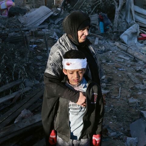 A Palestinian woman embraces a lightly injured boy as they check the rubble of a building following Israeli bombardment, on January 18, 2024 in Rafah in the southern Gaza Strip, amid ongoing battles between Israel and the Palestinian militant group Hamas.