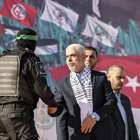 Yahia al-Sinwar (C), Gaza Strip chief of the Palestinian Islamist Hamas movement, shakes hands with a masked fighter of Hamas' Qassam Brigades during a rally marking the 35th anniversary of the group's foundation, in Gaza City on December 14, 2022. - Hamas will end talks on securing a prisoner exchange with Israel unless there is progress soon, the militant group's leader in the Gaza Strip said on December 14. Since Israel's 2014 invasion of the Gaza Strip, the Islamist group has held the bodies of Israeli 