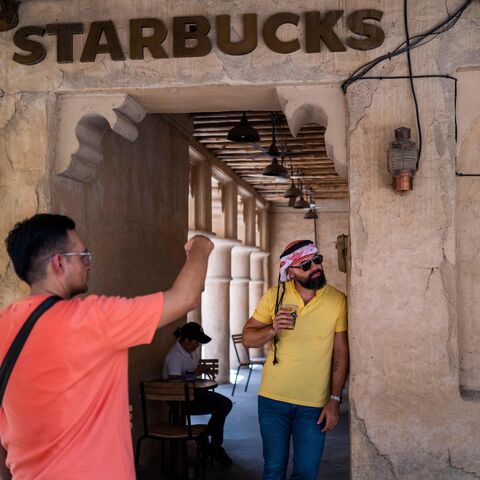 A man poses for video outside a Starbucks coffee shop in a market area in Dubai on May 18, 2023.