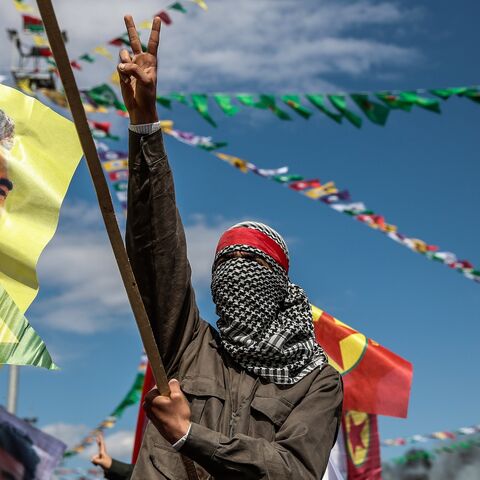 A Kurdish man wearing a mask flashes the "V" sign.