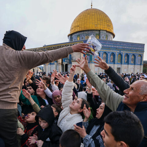 A volunteer distributes sweets to Muslims after special morning prayers to start the Eid al-Fitr festival, which marks the end of the holy fasting month of Ramadan, at the Al-Aqsa Mosque compound in Jerusalem on April 10, 2024.