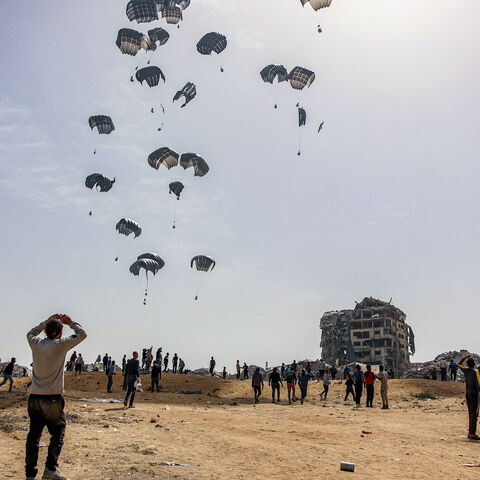 People rush to landing humanitarian aid packages dropped over the northern Gaza Strip on April 23, 2024 amid the ongoing conflict in the Palestinian territory between Israel and the militant group Hamas. 