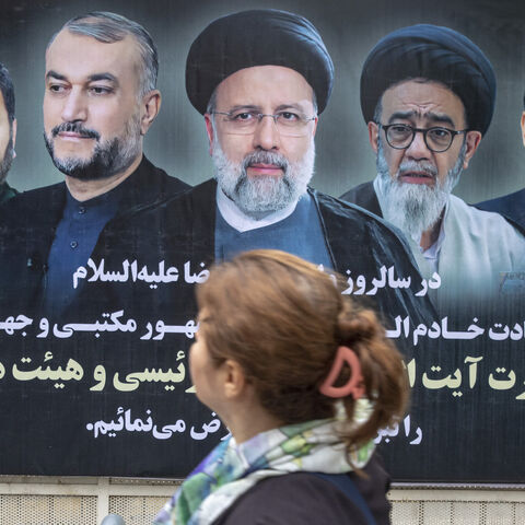An Iranian woman in Tehran passes by a poster of Iran's late president Ebrahim Raisi two days after his death on May 21, 2024.