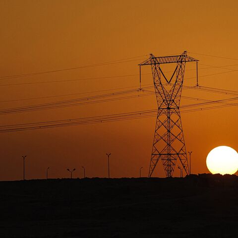 The sun sets behind high voltage transmission towers (electricity pylons) along a highway in El-Shorouk, a satellite city about 47 kilometers outside the city center of Cairo, on July 24, 2023. 