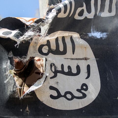 A member of Hashed Al-Shaabi (Popular Mobilization units) removes a sign on a lamp post bearing the logo of the Islamic State (IS) group on August 26, 2017. 