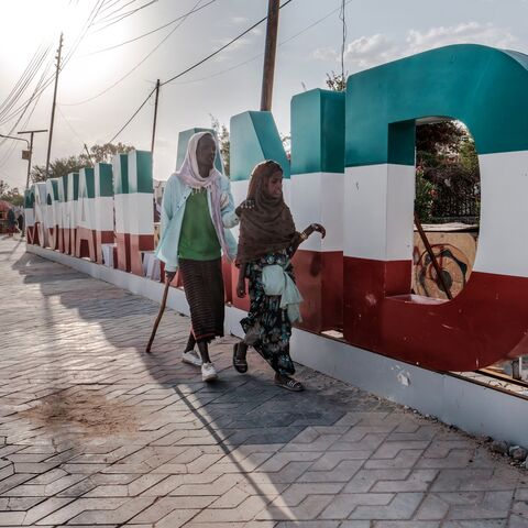 A blind man guided by a girl walk in front of a sign, in the city of Hargeisa, Somaliland, on September 16, 2021. - For 30 years, Somaliland has tried unsuccessfully to convince the world of its case for statehood, holding democratic elections and avoiding the anarchy that engulfed the rest of Somalia. (Photo by EDUARDO SOTERAS / AFP) (Photo by EDUARDO SOTERAS/AFP via Getty Images)