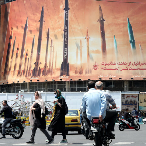 Motorists drive their vehicles past a billboard depicting Iranian missiles in Tehran on April 20, 2024, a day after Iran's state media reported explosions in the central province of Isfahan. 