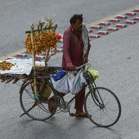 A vendor selling dates walks across a street in Islamabad on July 8, 2024, as cash-strapped Pakistan adopted a $68 billion budget laced with tax-raising measures on June 28, seeking to secure a new bailout from the IMF.