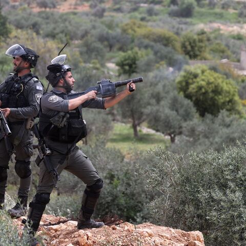 An Israeli soldier fires teargas at Palestinians during a protest in the village of Beita against a march by settlers to the nearby Israeli outpost of Eviatar, the occupied West Bank, April 10, 2023.