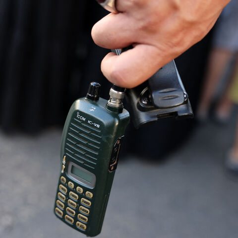 A man holds an Icom walkie talkie device after he removed the battery during the funeral of persons killed when hundreds of paging devices exploded in a deadly wave across Lebanon the previous day, in Beirut's southern suburbs on Sept. 18, 2024. 