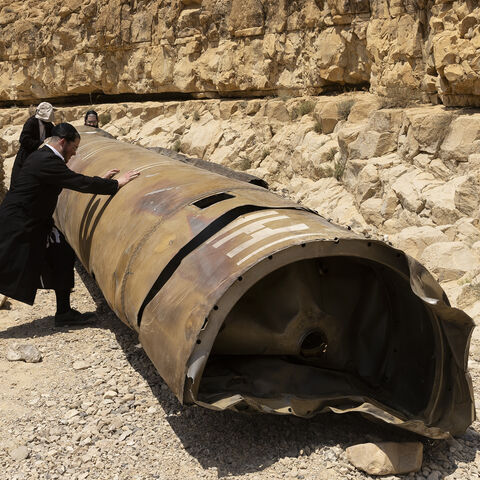 Ultra-Orthodox Jewish men roll a missile debris from Iran's aerial barrage on April 13, located at a channel near the city of Arad, Israel, April 30, 2024.