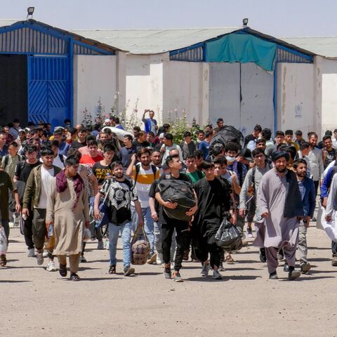 Afghan refugees walk with their belongings after deporting back from Iran at the Islam Qala border between Afghanistan and Iran, in the western Herat province on May 30, 2024. 