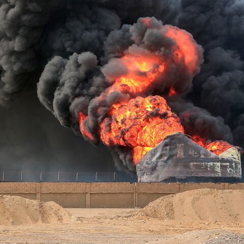 A man walks across from a raging fire at oil storage tanks a day after Israeli strikes on the port of Yemen's Houthi-held city of Hodeidah on July 21, 2024. 