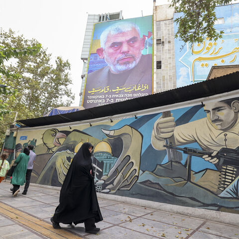 TOPSHOT - People walk past a billboard showing a portrait of newly appointed Hamas leader Yahya Sinwar (top) next to Palestine Square in the Tehran on August 12, 2024. (Photo by ATTA KENARE / AFP) (Photo by ATTA KENARE/AFP via Getty Images)