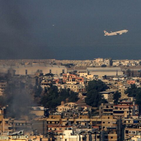 A Middle East Airlines commercial aircraft taking off from Beirut's international airport flies amid smoke billowing above the Lebanese capital's southern suburbs, in the aftermath of overnight Israeli airstrikes, on Sept. 28,2024.