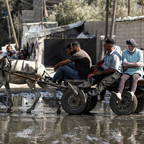 Displaced people ride on a donkey-drawn cart through a muddy puddle in Deir al-Balah in the central Gaza Strip on Sept. 30, 2024.