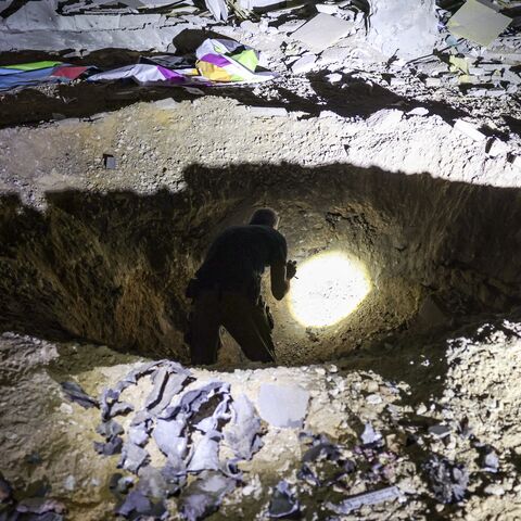 Members of Israel's Home Front Command and police forces inspect a crater left by an exploded projectile at a heavily damaged school building in Israel's southern city of Gedera.