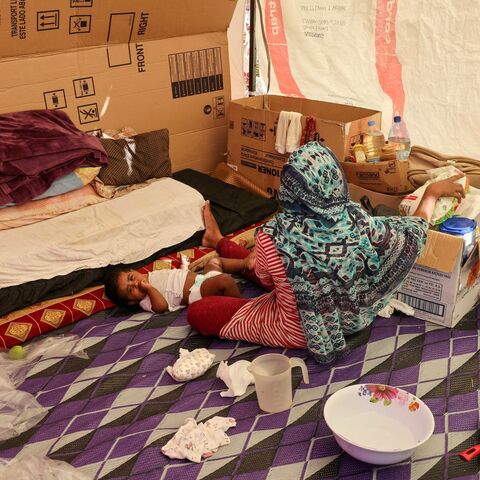 A displaced Bangladeshi woman and her child sit inside their makeshift shelter on the seaside promenade in the Biel area of Beirut, Oct. 17, 2024.