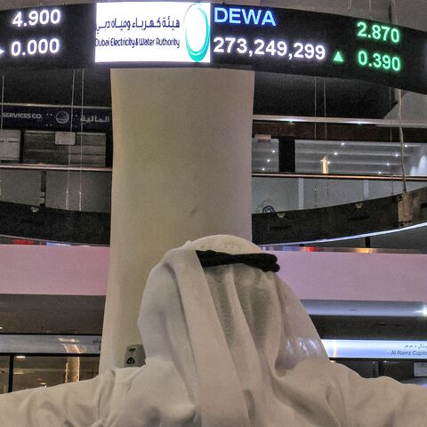 A man watches stock movements on a display at the Dubai Financial Market stock exchange in the Gulf emirate on April 12, 2022. 