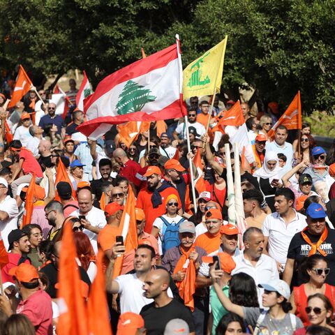 Supporters wave national flags as well as orange flags of the Free Patriotic Movement and the yellow flag of the Hezbollah movement, as Lebanon's outgoing President Michel Aoun leaves the presidential palace in Babda, at the end of his mandate, east of the capital Beirut, on October 30, 2022.