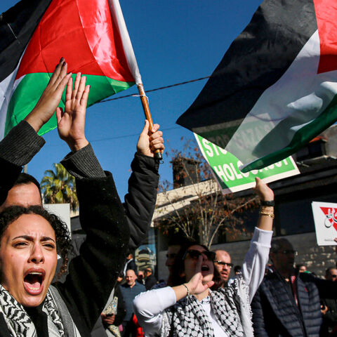 People wave Palestinian and Jordanian flags and chant slogans as they march during a demonstration near the US embassy in the capital Amman in solidarity with the people of Gaza on December 15, 2023, amid the continuing battles between Israel and the militant group Hamas. (Photo by Khalil MAZRAAWI / AFP) (Photo by KHALIL MAZRAAWI/AFP via Getty Images)