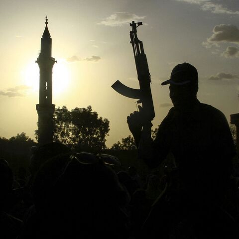 A fighter loyal to Sudan's army, chief Abdel Fattah al-Burhan, holds up a weapon against the backdrop of a mosque, during a graduation ceremony in the southeastern Gedaref state on May 27, 2024. 