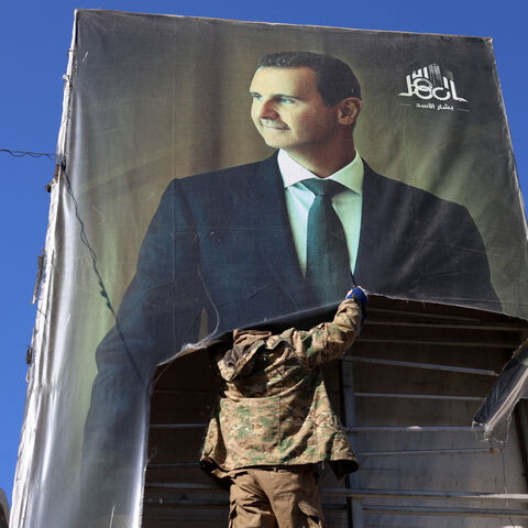 An anti-government fighter tears down a portrait of Syria's President Bashar al-Assad in Aleppo, after jihadists and their allies entered the northern Syrian city, on November 30, 2024.