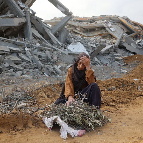 TOPSHOT - A elderly woman sits in front of a destroyed building to take a rest as she collects tree branches to light a fire in Nuseirat in the central Gaza Strip after Israeli shelling of the camp stopped on November 29, 2024, amid the ongoing war in the Palestinian territory between Israel and Hamas. (Photo by Eyad BABA / AFP) (Photo by EYAD BABA/AFP via Getty Images)