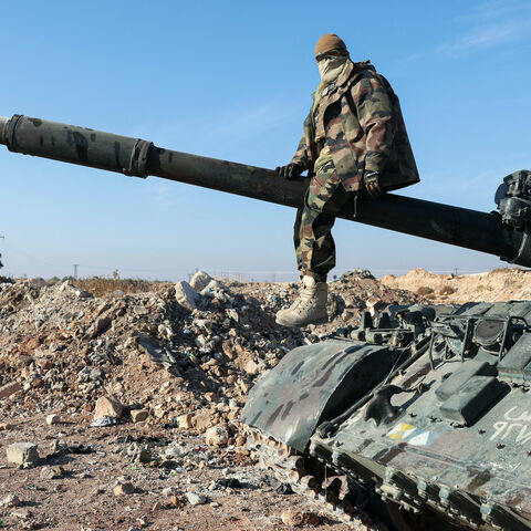 A militant poses for a picture after anti-government fighters seized Syrian army military equipment and vehicles that were abandoned on the highway to Damascus, as they reach the town of Suran north of Syria's Hama city on Dec. 3, 2024. 