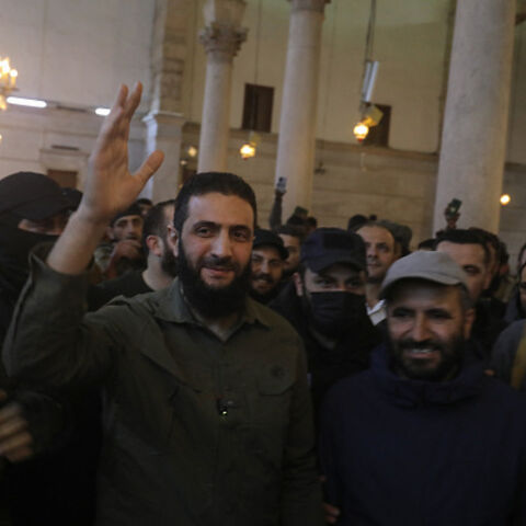 The leader of Syria's Islamist Hayat Tahrir al-Sham (HTS) group that headed a lightning rebel offensive snatching Damascus from government control, Abu Mohammed al-Jolani, waves to the crowd before addressing them at the capital's landmark Umayyad Mosque on December 8, 2024. Jolani, now using his real name Ahmed al-Sharaa, gave a speech as the crowd chanted "Allahu akbar (God is greatest)," a video shared by the rebels on their Telegram channel showed. (Photo by Abdulaziz KETAZ / AFP) (Photo by ABDULAZIZ KE