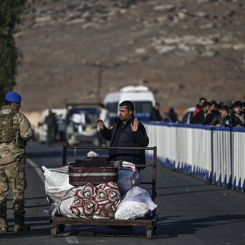 A Syrian refugee gestures as she speaks with Turkish soldiers at Cilvegozu crossborder gate before entering in Syria at Reyhanli district in Hatay, on December 9, 2024. Islamist-led rebels declared on December 8, 2024, that they have taken the Syrian capital in a lightning offensive, sending President Bashar al-Assad fleeing and ending five decades of Baath rule in Syria. (Photo by Ozan KOSE / AFP) (Photo by OZAN KOSE/AFP via Getty Images)