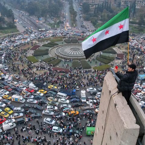 An aerial view shows a Syrian man waving the independence-era Syrian flag at Damascus' central Umayyad Square, on Dec. 11, 2024. 