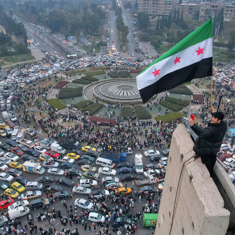 An aerial view shows a Syrian man waving the independence-era Syrian flag at Damascus' central Umayyad Square on Dec. 11, 2024. 