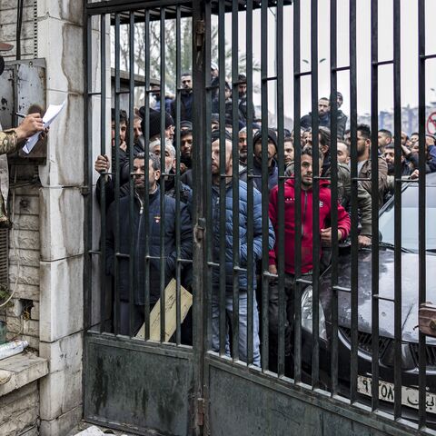 A member of Syria's transitional government security forces calls the names of persons queueing up at a center for handing over small arms and security registration with the new authorities, in Damascus, on Dec. 24, 2024.